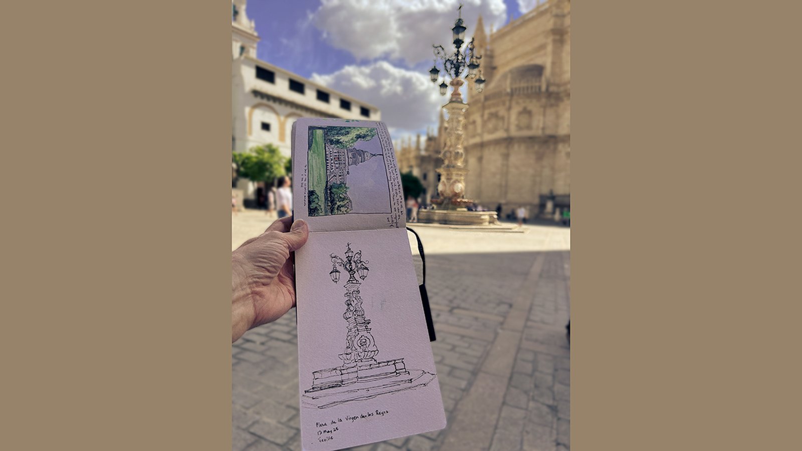 Sketchbook held open in Plaza de la Virgen de los Reyes, Seville, showing fountain sketch with cathedral in background