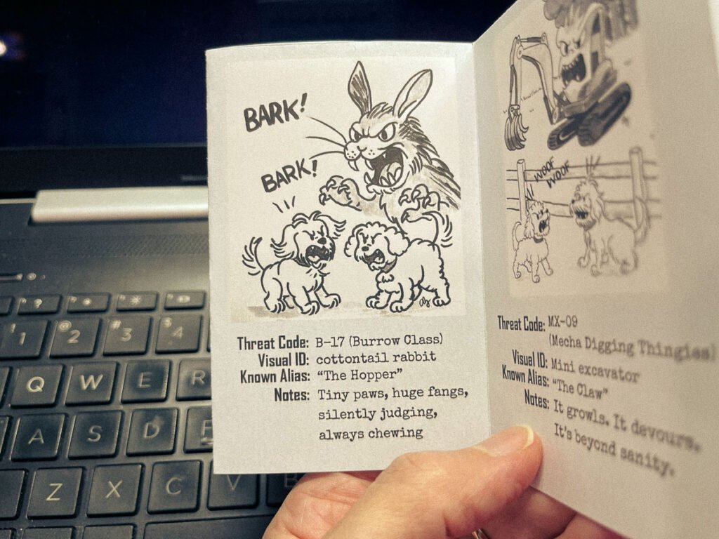 Open zine page showing cartoon dogs barking at a large, villainous rabbit and a construction excavator labeled as threats.