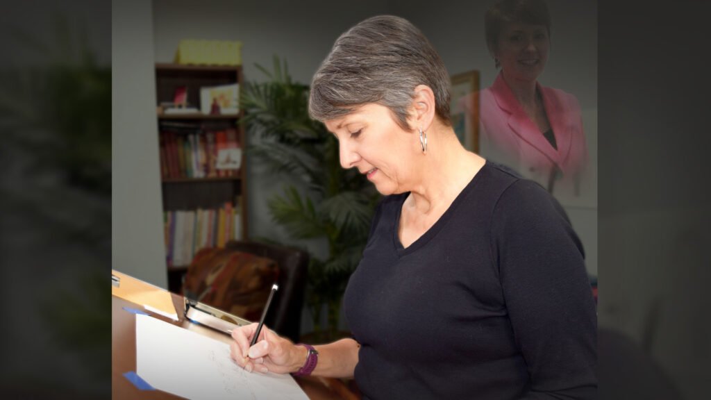 Woman drawing at a desk in a home studio, with a faint, ghosted image of her younger self in the background.