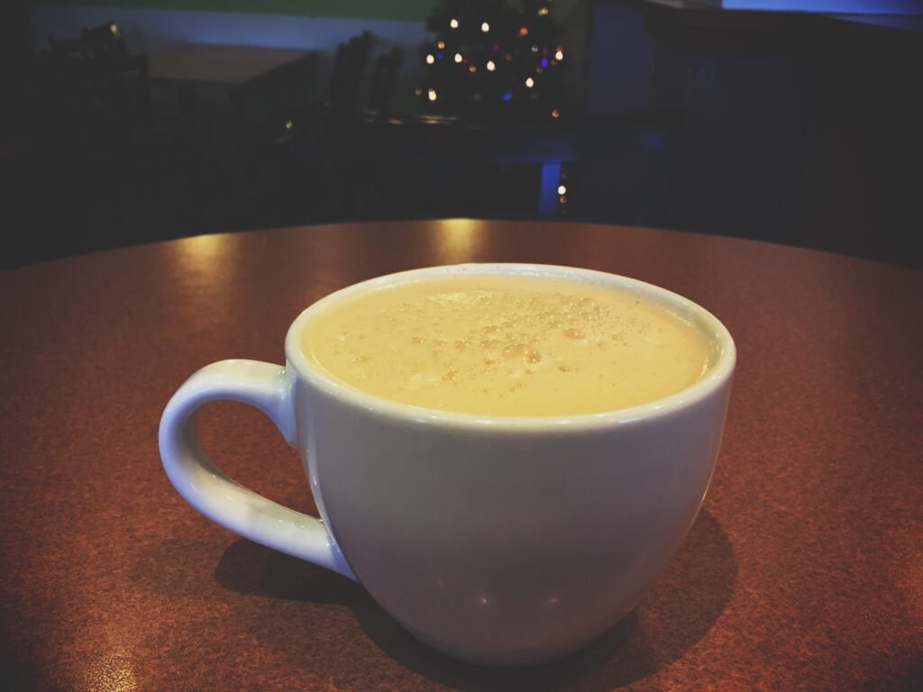 Eggnog in a white coffee cup sits on a wooden table