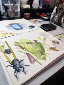 an artist's table with a finished watercolor work and palette