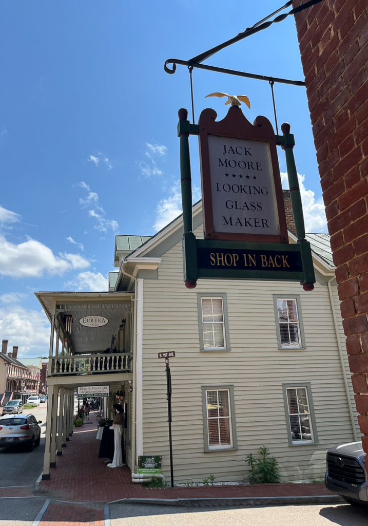 Photograph of the Jack Moore Looking Glass Maker sign hanging above the Eureka Inn in downtown Jonesborough.