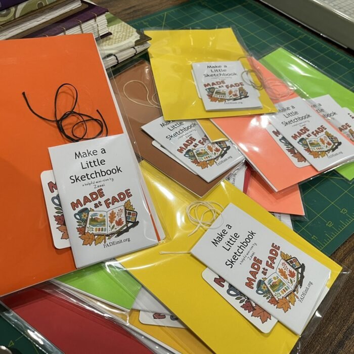 Sketchbook-making kits in clear bags on a cutting mat, with colorful covers, binding thread, “Made at FADE” stickers, and “Make a Little Sketchbook” instruction zines.